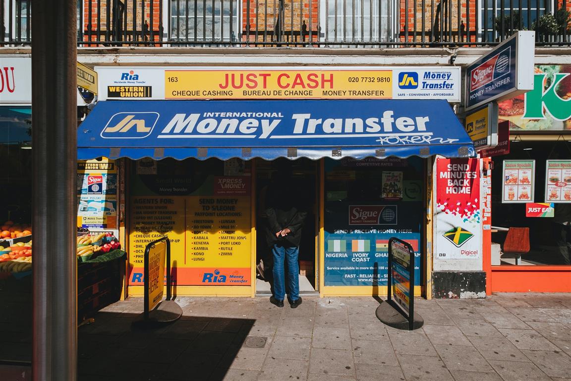 Street scene of a man waiting in line at a money transfer shop in London, notoriously dodgy places - Photo by Alistair MacRobert on Unsplash 