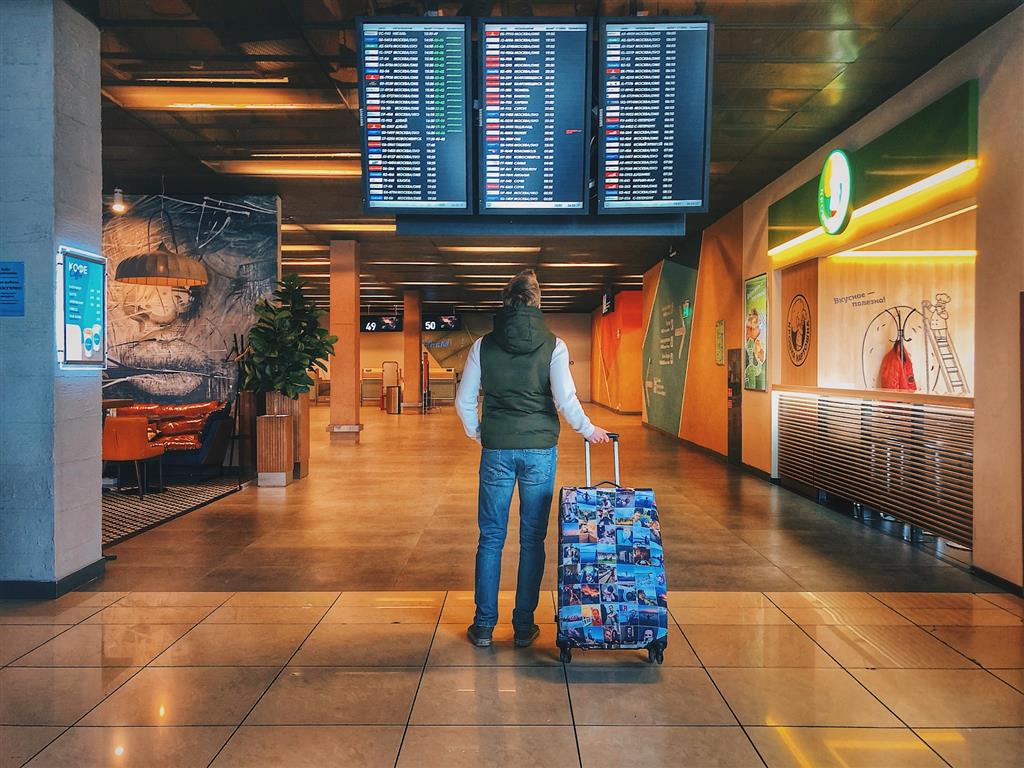 Man looking at a departure board in an airport - Photo by Danila Hamsterman on Unsplash